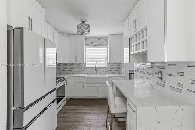 kitchen featuring stainless steel electric range oven, white cabinets, a sink, and freestanding refrigerator