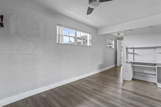 unfurnished bedroom featuring ceiling fan, a textured ceiling, baseboards, and wood finished floors