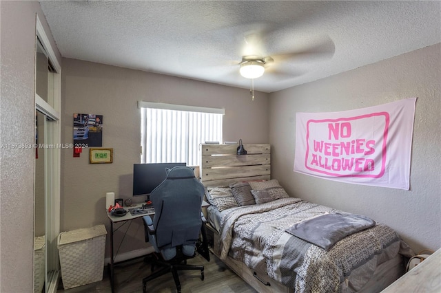 bedroom with hardwood / wood-style flooring, a textured ceiling, and ceiling fan