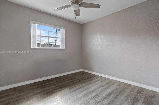 unfurnished room with a textured ceiling, wood finished floors, a ceiling fan, and baseboards