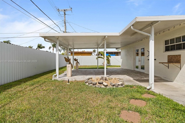 view of yard featuring a fenced backyard, a patio, a carport, and french doors