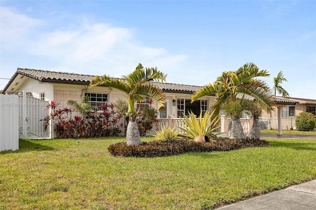 mediterranean / spanish-style house with fence, a front lawn, and a tiled roof