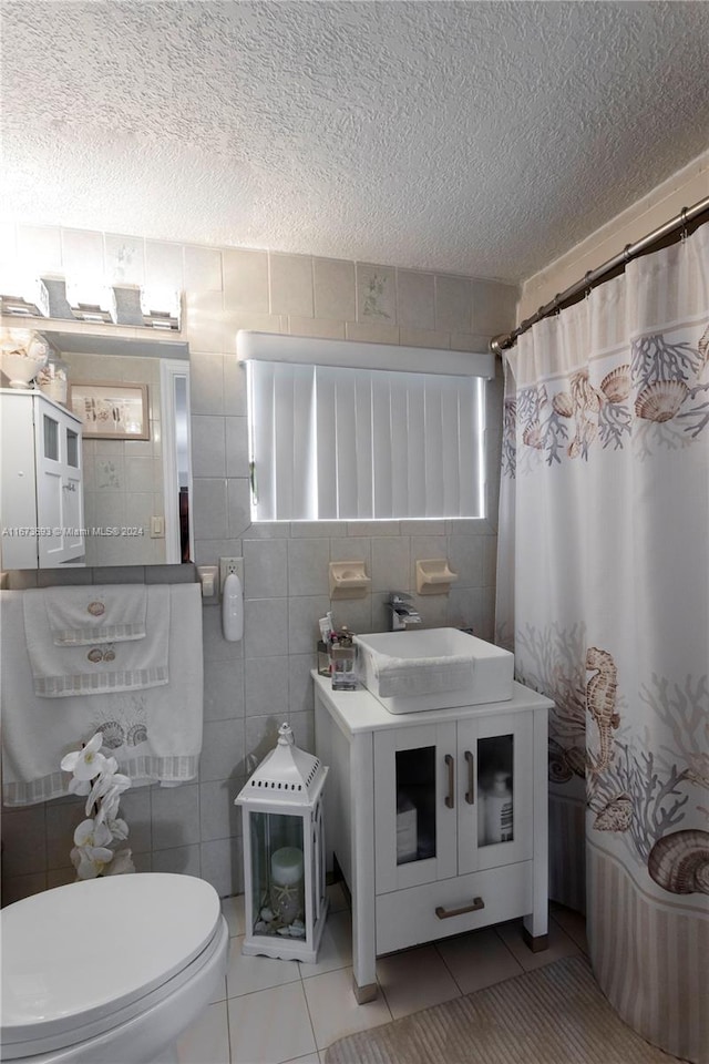 bathroom with vanity, a textured ceiling, tile walls, and toilet