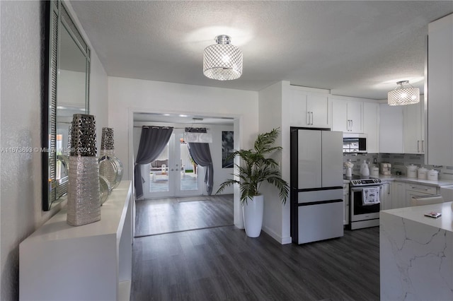 kitchen with stainless steel appliances, white cabinets, a textured ceiling, and dark wood-type flooring