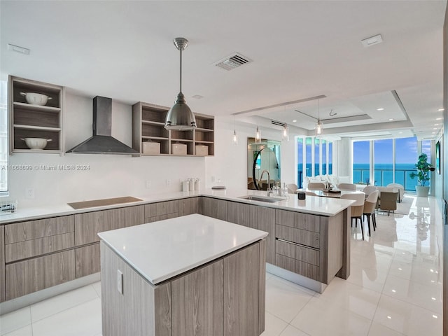 kitchen with sink, wall chimney range hood, black electric cooktop, a tray ceiling, and a water view