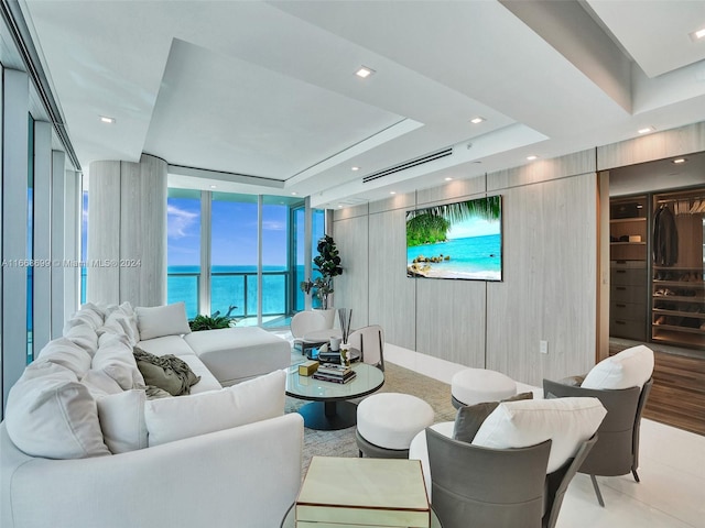 living room featuring a water view, expansive windows, and a tray ceiling