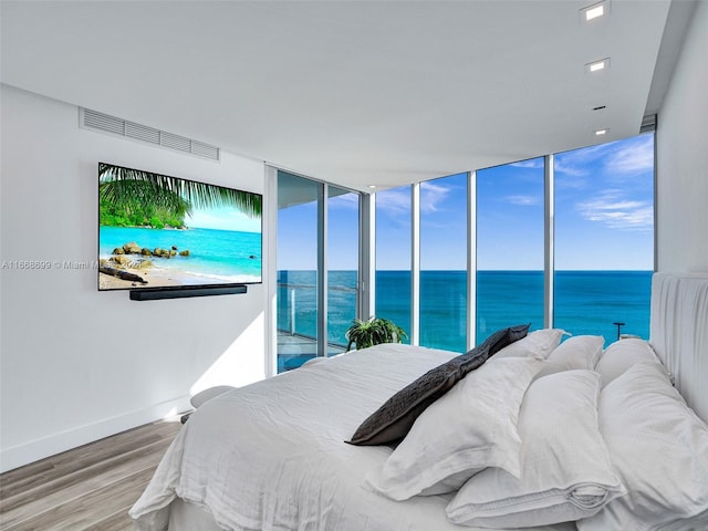 bedroom with access to exterior, expansive windows, and wood-type flooring