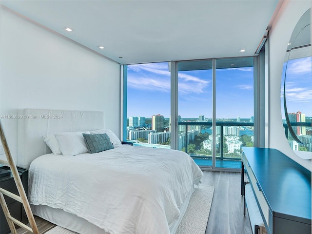 bedroom featuring expansive windows, hardwood / wood-style floors, and multiple windows