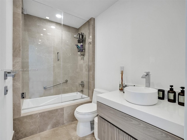 full bathroom with bath / shower combo with glass door, tile patterned floors, vanity, and toilet