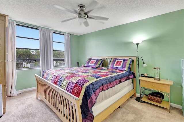 bedroom featuring light carpet, a textured ceiling, and ceiling fan