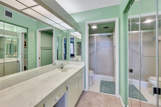 bathroom featuring toilet, a textured ceiling, vanity, and a shower with door