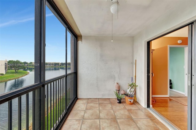 unfurnished sunroom with a water view and ceiling fan