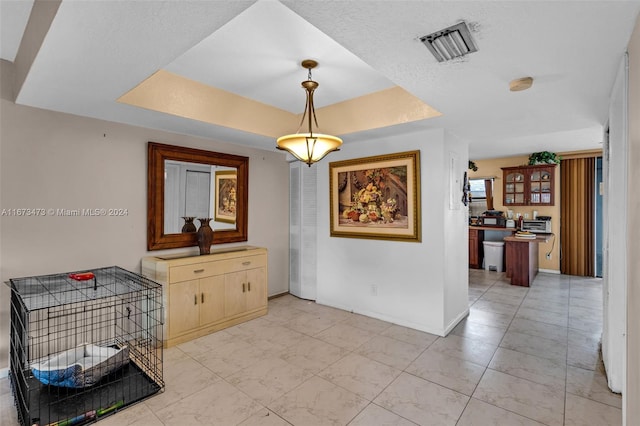 hall featuring a textured ceiling and a tray ceiling