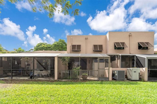 back of property with a sunroom, a yard, and cooling unit