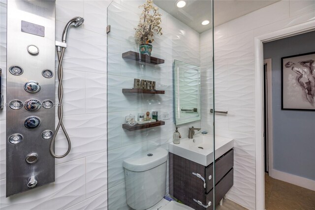 bathroom with tile walls, a tile shower, vanity, and toilet