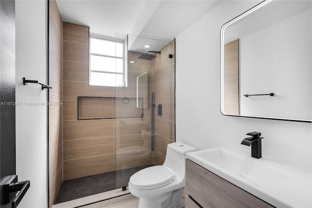 bathroom featuring tiled shower, vanity, and toilet