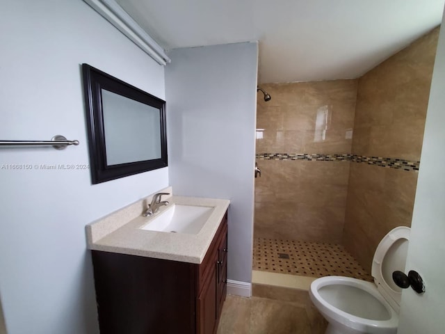 bathroom featuring toilet, vanity, and tiled shower