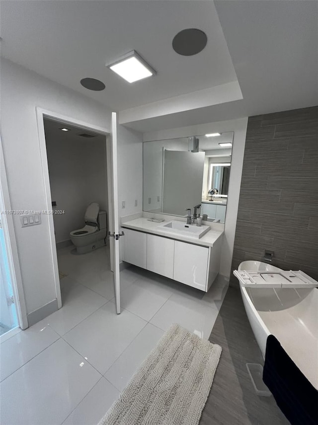 bathroom featuring a tub, vanity, tile walls, tile patterned flooring, and toilet