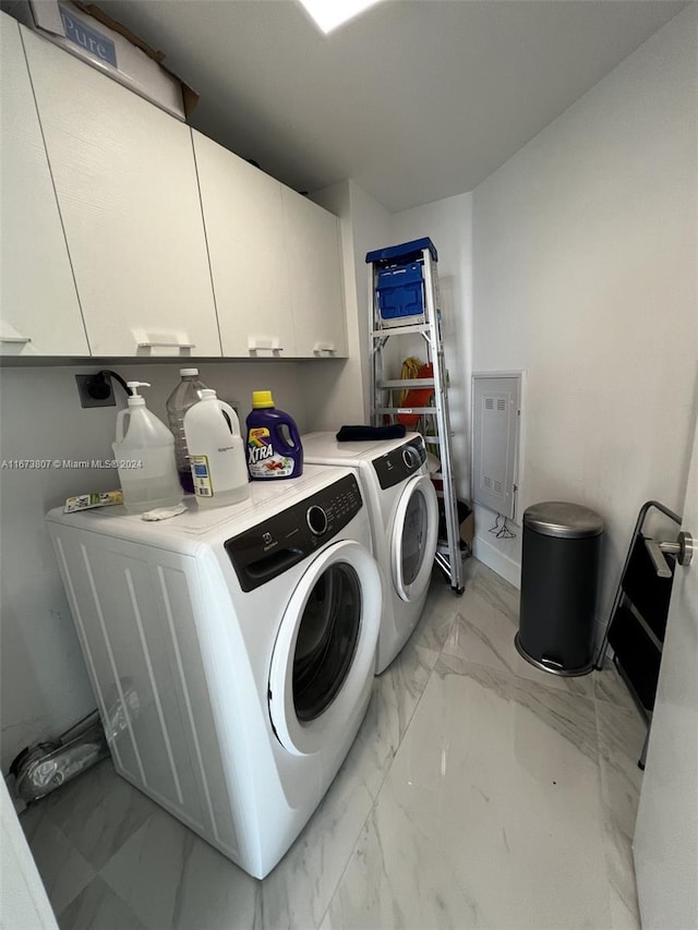 laundry room with separate washer and dryer and cabinets