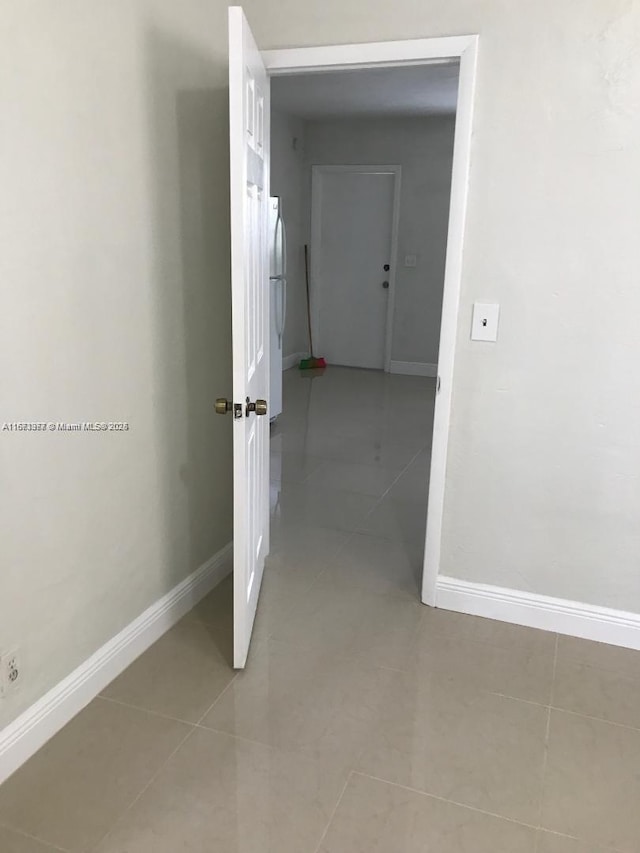 hallway featuring baseboards and light tile patterned floors