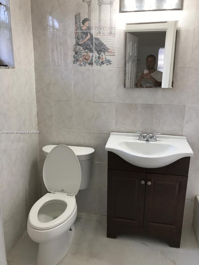 bathroom featuring tile walls, marble finish floor, vanity, and toilet