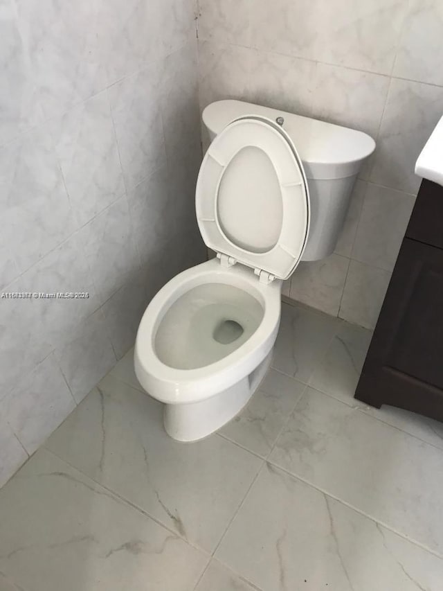 bathroom with marble finish floor, vanity, and toilet