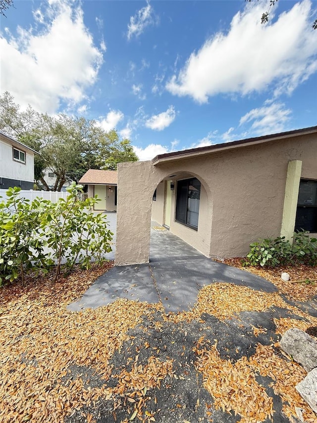 exterior space featuring a patio area, fence, and stucco siding