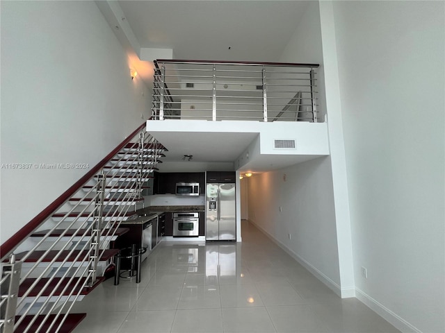 stairway featuring a towering ceiling and tile patterned floors