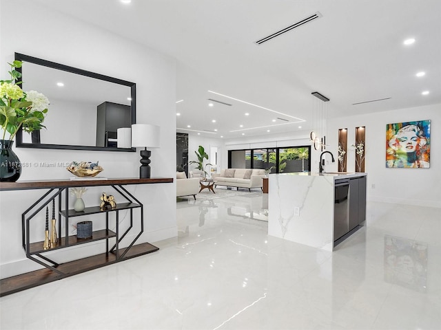 interior space with light stone countertops, stainless steel dishwasher, sink, hanging light fixtures, and light tile patterned floors