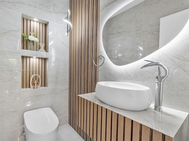 bathroom featuring vanity, tile walls, and toilet