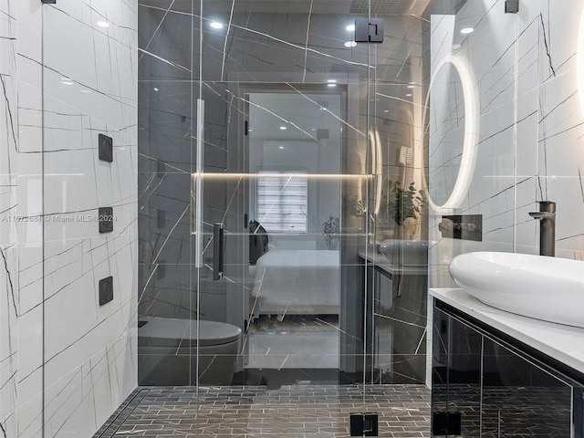 bathroom featuring a shower with shower door, vanity, and tile walls