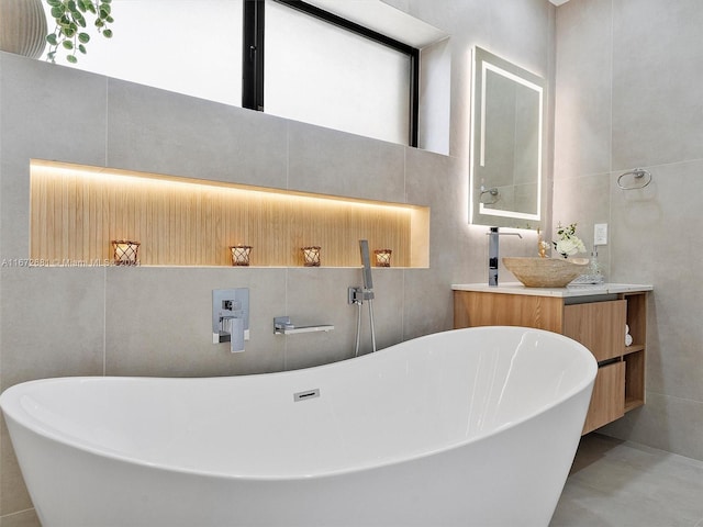 bathroom with a bathtub, vanity, and tile walls