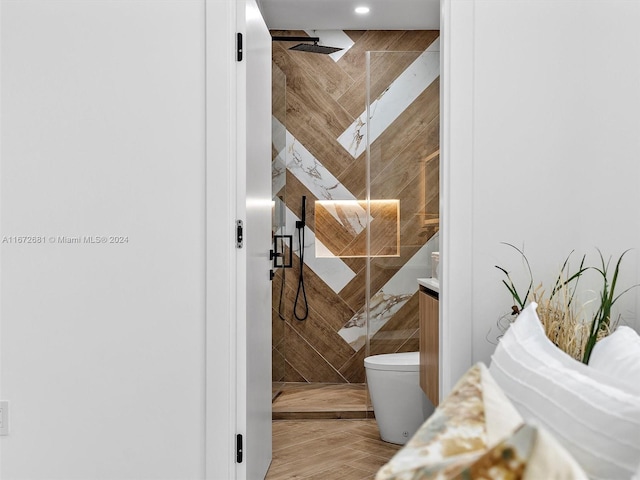 bathroom featuring vanity, tiled shower, toilet, and tile walls