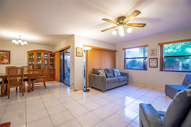 tiled living room with ceiling fan with notable chandelier