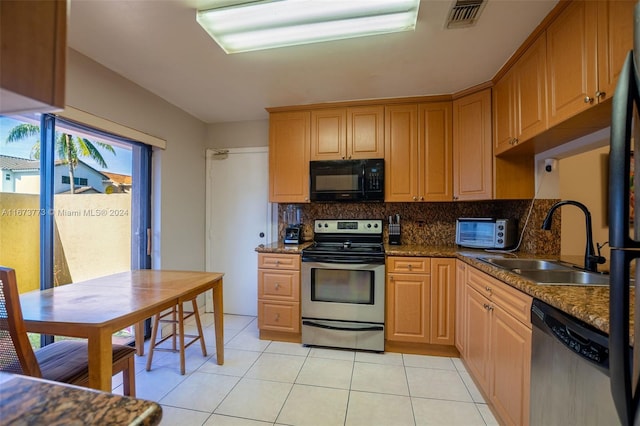 kitchen with light tile patterned floors, sink, backsplash, stainless steel appliances, and dark stone counters