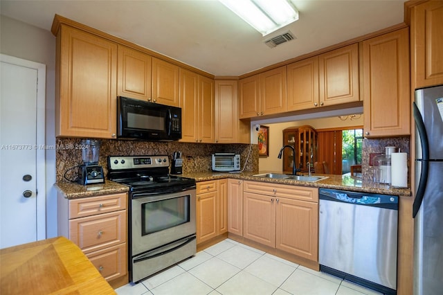 kitchen featuring light tile patterned floors, appliances with stainless steel finishes, sink, and decorative backsplash