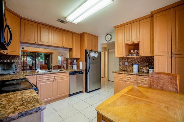 kitchen featuring black appliances, sink, light tile patterned floors, and stone countertops