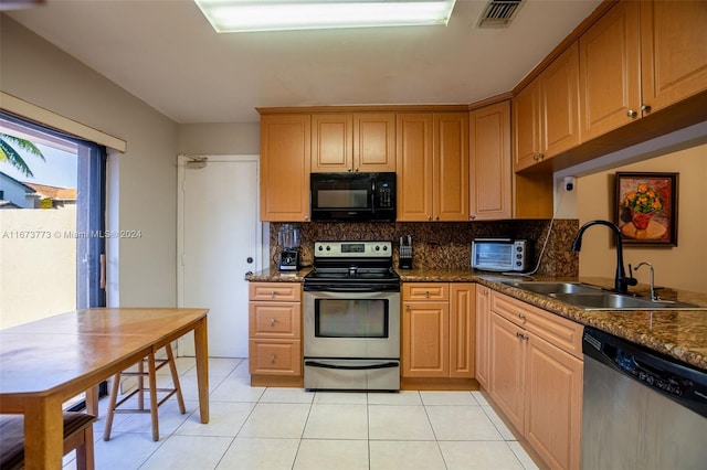 kitchen with tasteful backsplash, dark stone countertops, sink, appliances with stainless steel finishes, and light tile patterned floors