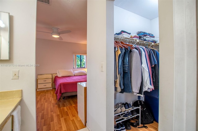 walk in closet with light wood-type flooring and ceiling fan