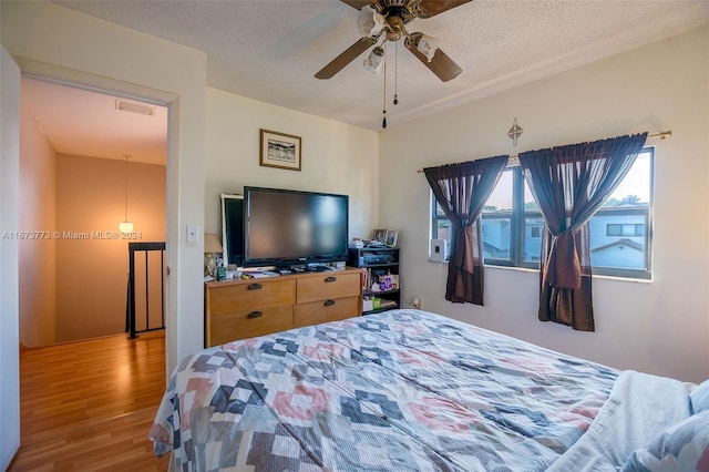 bedroom with a textured ceiling, light wood-type flooring, and ceiling fan