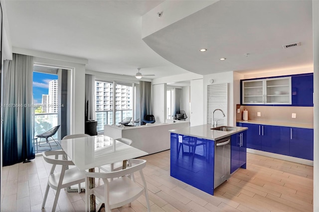 kitchen with a kitchen island with sink, blue cabinets, light hardwood / wood-style flooring, sink, and dishwasher