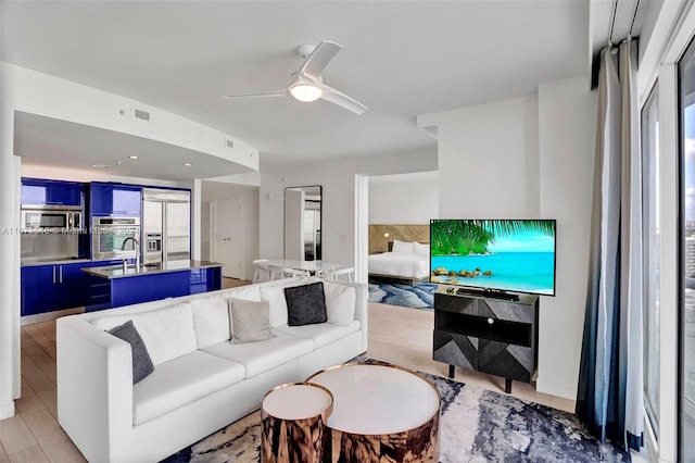 living room with ceiling fan, plenty of natural light, and light hardwood / wood-style floors