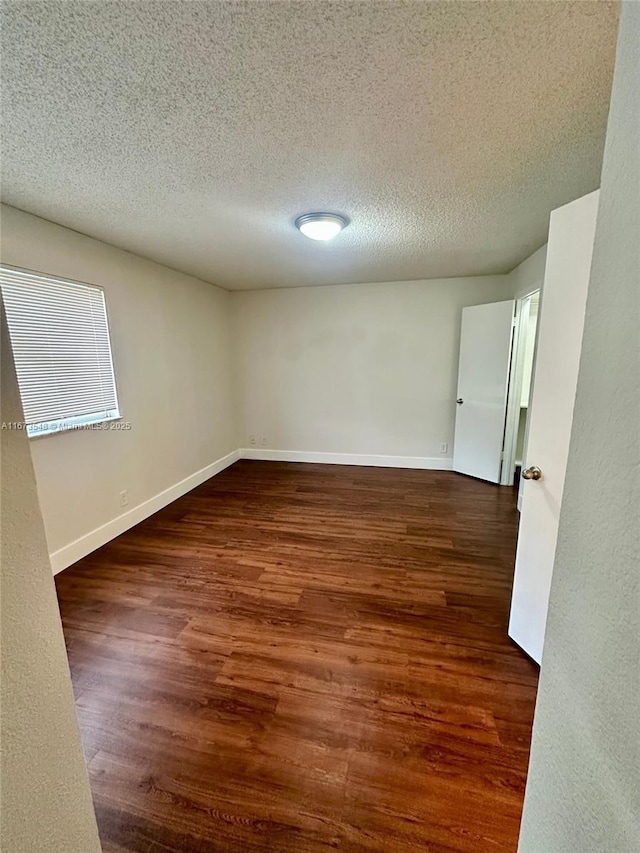 spare room featuring dark hardwood / wood-style floors and a textured ceiling