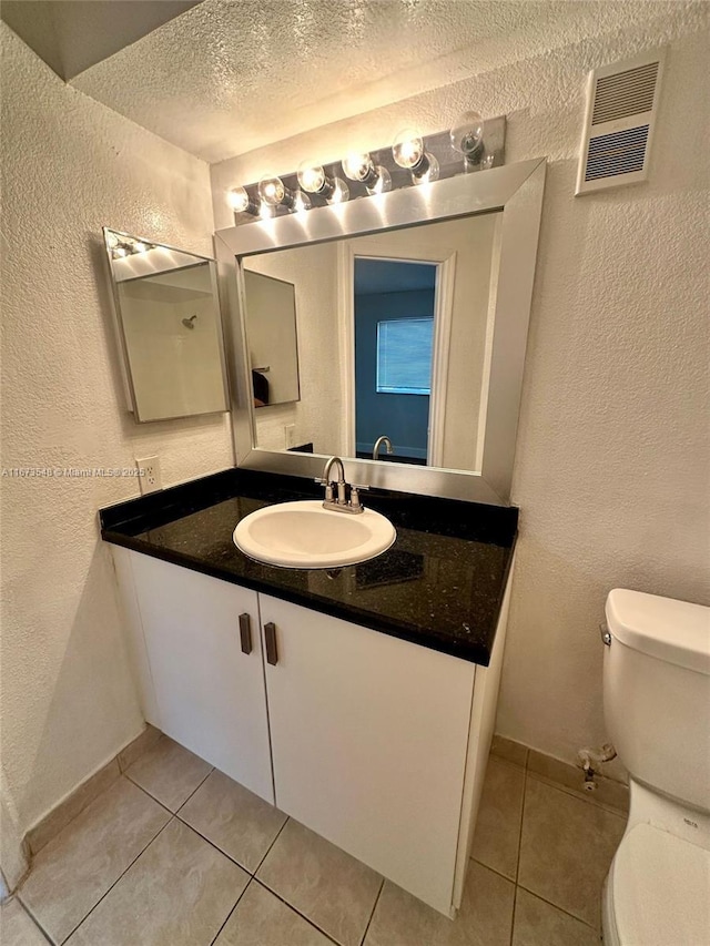 bathroom with tile patterned floors, vanity, toilet, and a textured ceiling