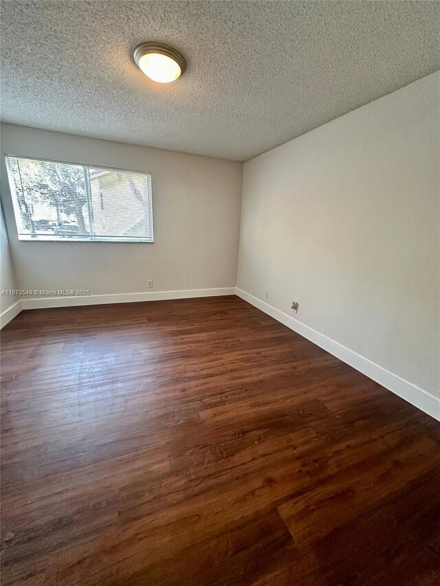 unfurnished room with dark hardwood / wood-style flooring