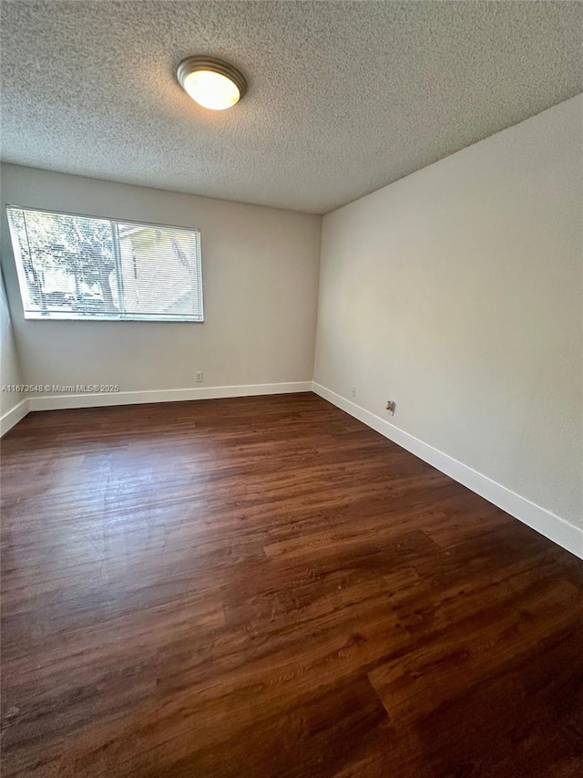 spare room featuring dark hardwood / wood-style flooring and a textured ceiling