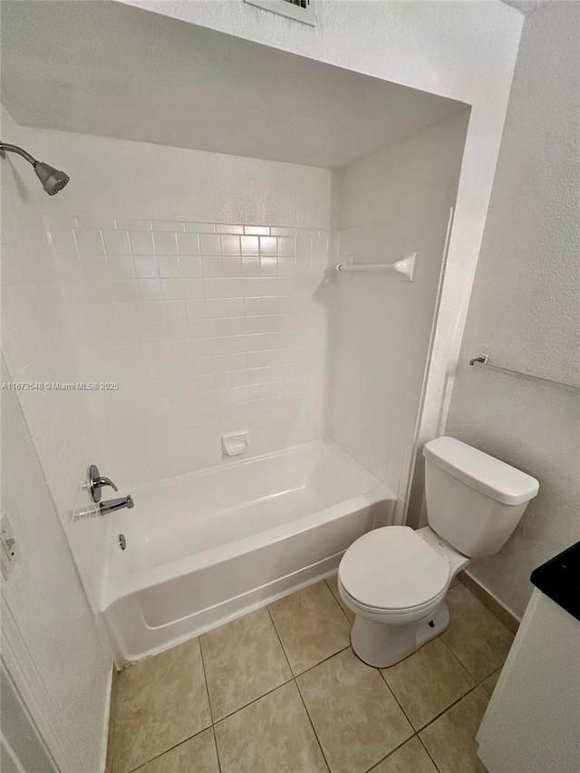 bathroom with toilet, tiled shower / bath combo, and tile patterned flooring