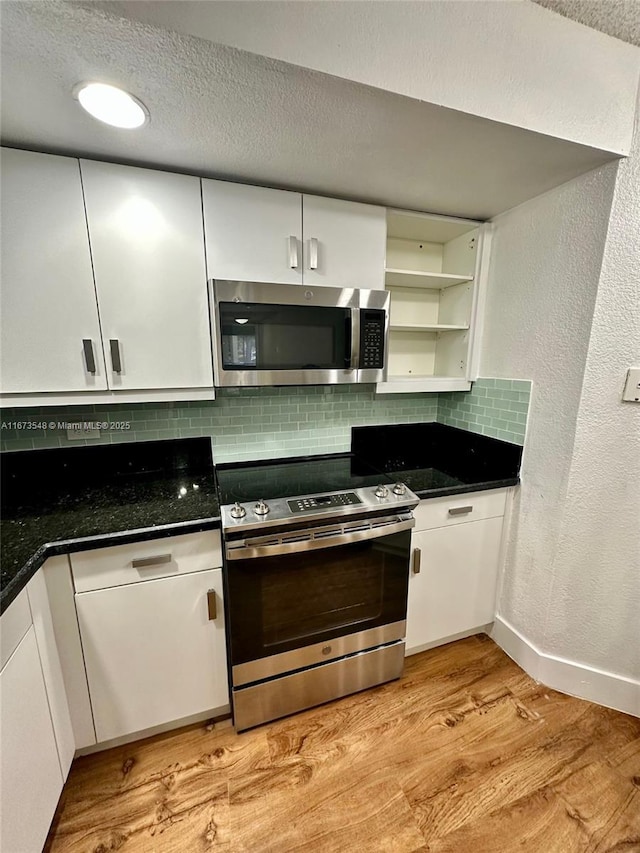 kitchen featuring stainless steel appliances, white cabinets, light hardwood / wood-style floors, and decorative backsplash