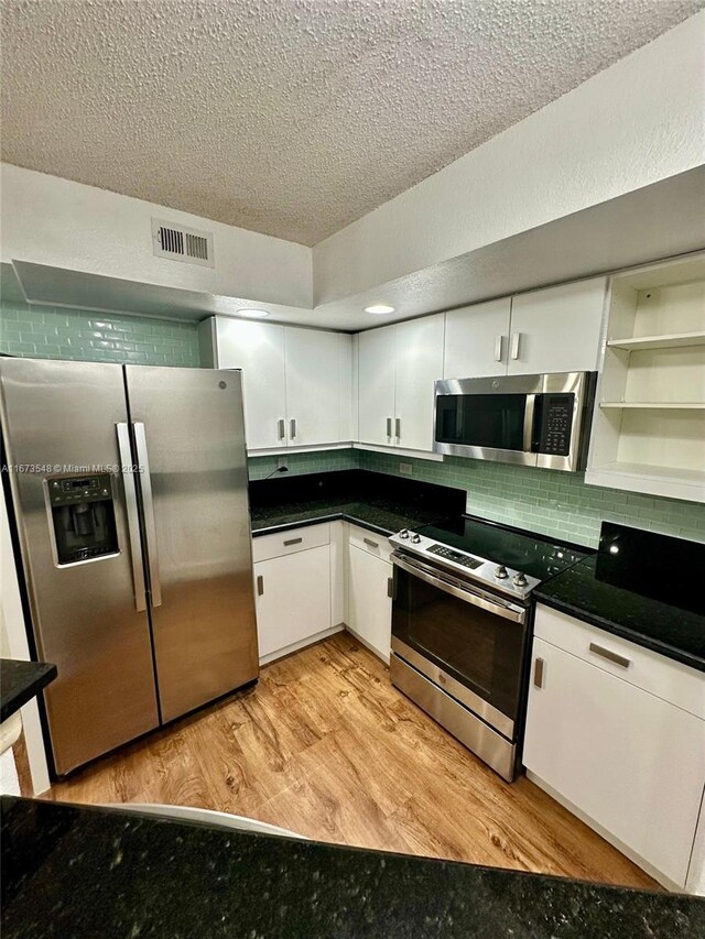 kitchen featuring tasteful backsplash, stainless steel appliances, light wood-type flooring, and white cabinets