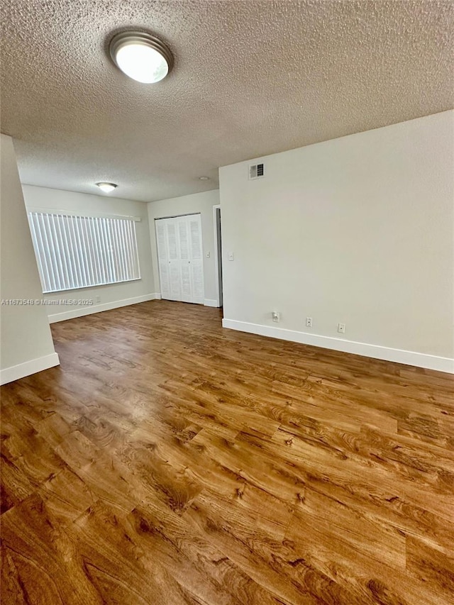 unfurnished room with wood-type flooring and a textured ceiling